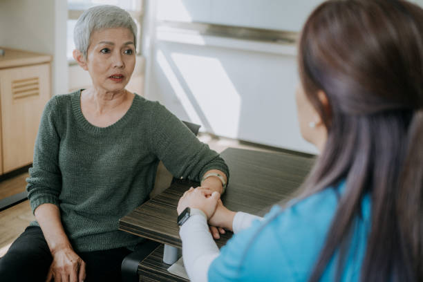 An Asian Chinese female psychologist and a mature woman are discussing the woman's problems during a therapy session in a comfortable office. - Professional therapist concept.